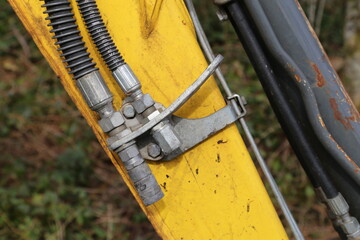 A closeup view of the hydraulic arm on a yellow excavator.