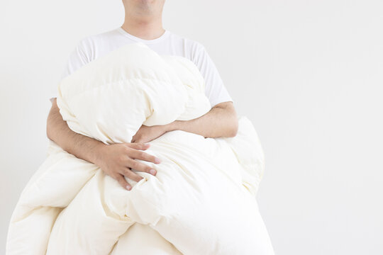 日干しした冬用の掛け布団を持つ、半袖シャツを着た男性