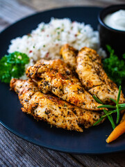 Steamed chicken nuggets, rice and small carrots on wooden table
