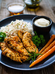 Steamed chicken nuggets, rice and small carrots on wooden table
