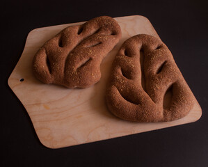 Domowe bochenki chleba w kształcie liścia umieszczone na drewnianej desce