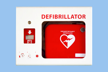 AED cardiac defibrillator box isolated on solid blue wall - obrazy, fototapety, plakaty