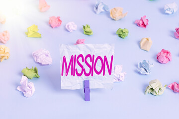 Handwriting text Mission. Conceptual photo important task are given to do one that involves traveling Colored crumpled papers empty reminder blue floor background clothespin