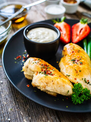 Roasted chicken fillets with green beans and strawberries on wooden table
