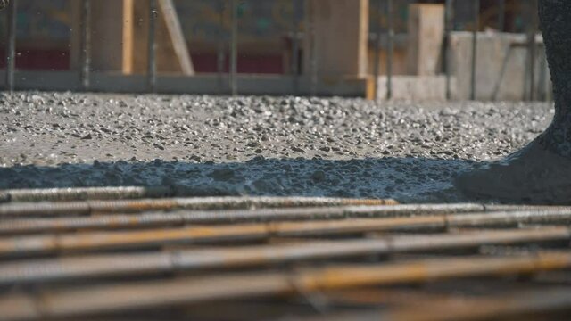 Teamwork. A team of builders pours concrete mixture of the metal reinforcement of the foundation of the house. The technology of building a country house.
