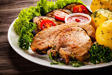 Barbecue beef steak fried potatoes and vegetables on wooden table
