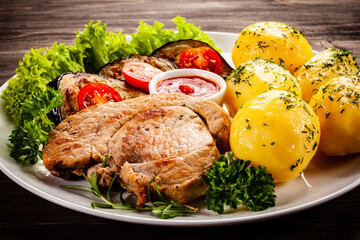 Barbecue beef steak fried potatoes and vegetables on wooden table
