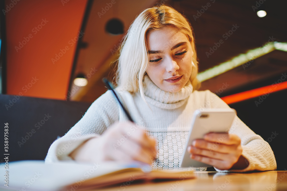 Poster young woman making notes using organizing application on cellular for planning tasks and learning pr