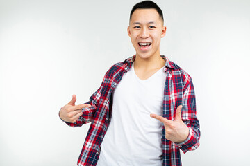 smiling young Asian man in a shirt wide open shows blank space on his white T-shirt on an isolated white studio background
