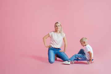 Positive young mother with a young son. Beautiful blonde with her baby on a skateboard,