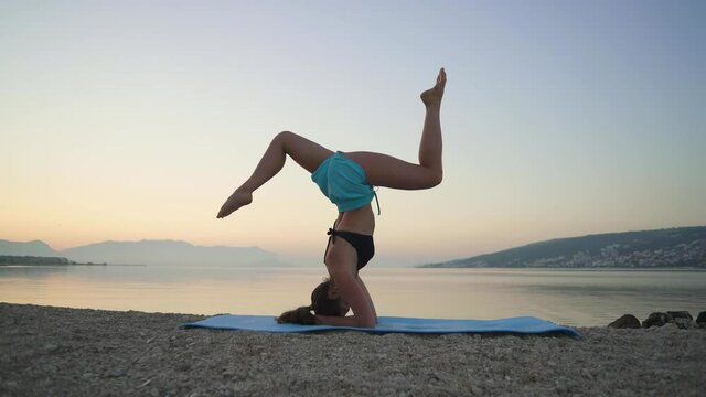 Beautiful girl warms up and practices yoga by the sea. Sports, yoga, beach.