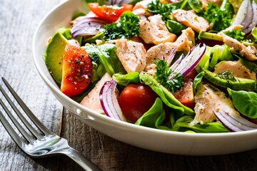 Salmon salad - roasted salmon and vegetables on wooden background

