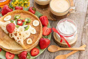 Edible bear with strawberries on pancakes and a jar of sour cream.