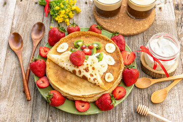 Delicious Breakfast of pancakes with strawberries, bananas, kiwi and cream.