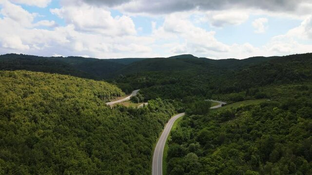 Aerial view drone image of curvy mountain road asphalt with serpentine trough the trees green forest in day in summer or autumn nature taken in Serbia Tresibaba Knjazevac in Balkans journey concept