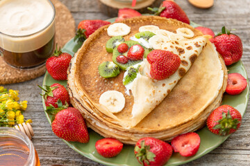 Pancakes with kiwi, bananas and strawberries for Breakfast. An edible bear of fruit and berries covered with a pancake.