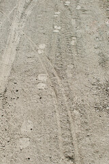 Human footprints and tire trucks on the dusty ground / pathway / footpath in the forest / on the field 