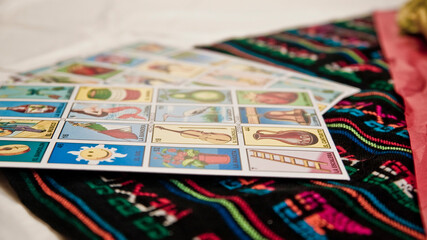 an elegant table adorned with a Mexican handicraft tablecloth, on this a fun typical Mexican game called loteria, with different numbered figures even without the sheets being distributed to start the