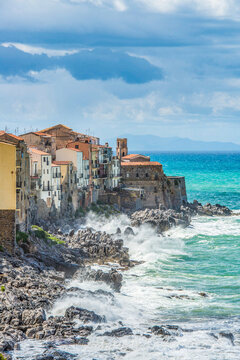 Waves breaking against the coastline of picturesque town of Cefalu. The church Chiesa dell Itria dominates the north point