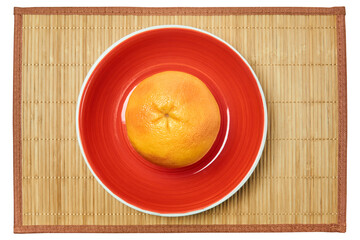 ripe yellow grapefruit on a red plate on a cane serving mat