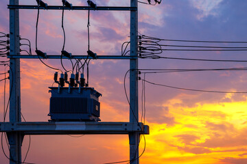 Electric power transformer on cement pole with messy cable wires with beautiful sky while sunset or...