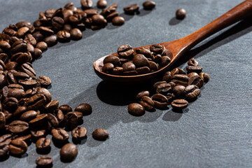 A scattering of freshly roasted coffee beans on a gray stone. Grains of arabica. A natural stone.