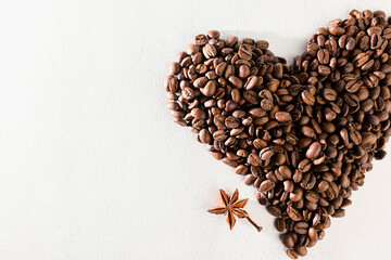coffee beans laid out in the shape of a heart on a white scuffed background. Concept of a popular invigorating drink. selective focus.