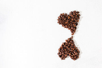 coffee beans laid out in the shape of two hearts on a white scuffed background. The concept of a popular invigorating drink and love. selective focus.