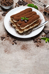 Classic tiramisu dessert on ceramic plate on concrete background