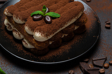 Classic tiramisu dessert on ceramic plate on concrete background