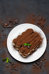 Classic tiramisu dessert on ceramic plate on concrete background