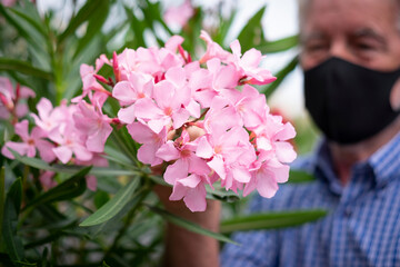 Defocused senior man wearing a black mask because of the coronavirus, in the foreground beautiful...