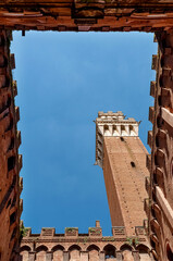 Looking up view from inner courtyard on medieval red brick tower Torre del Mangia in Palazzo...