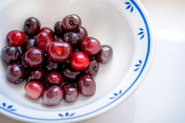 white bowl with fresh cherries over white background