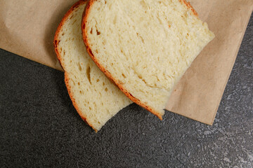 two slices of bread on bread paper on a black table copies space flat lay
