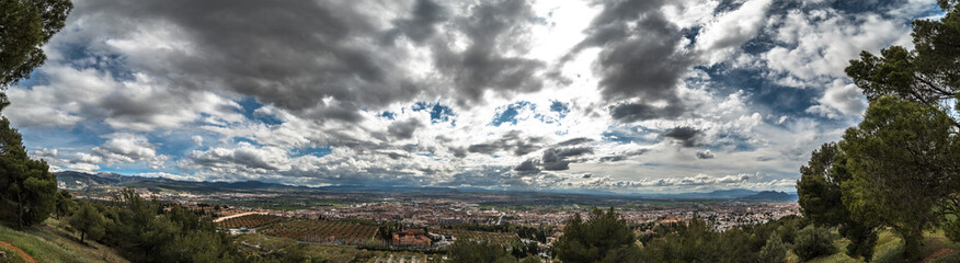 Wide angle landscape view of the city of Granada in Spain. The sky in black clouds