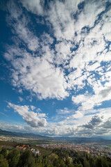 White clouds against the blue sky above the forest and field. Clouds on blue sky above green meadow