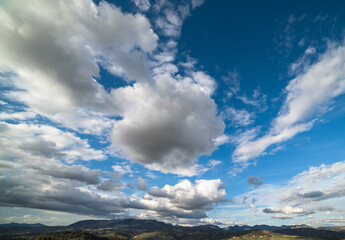 White clouds on blue sky above mountains.