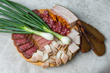 Traditional salt fat, bacon, salami, green onion and black bread are served on the plate as native cold meal. Closeup photo of Russian, Byelorussian and Ukranian appetizer for dinner. 