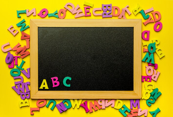 Letters ABC on blackboard surrounded by wooden letters.
