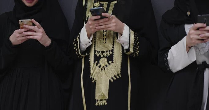 Beautiful muslim women in fashionable dress with hijab using mobile phone over chalkboard backgorund
