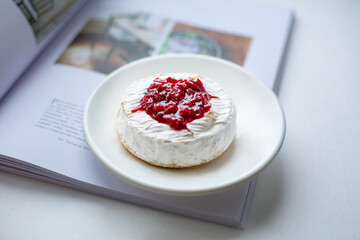 Camembert cheese baked with berry sauce on the background of the magazine