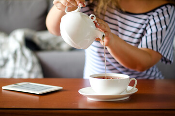 Cozy home interior with teapot, cup of tea and eBook