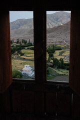 Ladakh Fields and Tibetan Buddhist Stupa seen from the wooden window frame of a Monastery (Northern India)