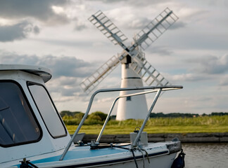 Front end of pleasure boat moored in Thurne Dyke with the infamous Thurne windmill in soft focus in...