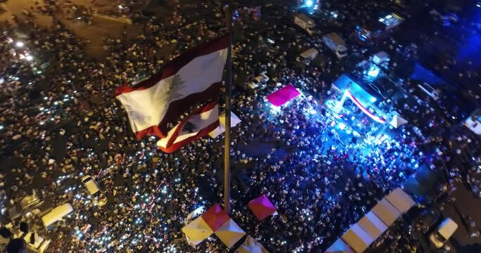 Beirut, Lebanon 2019 : night drone shot around Lebanese flag in Martyr square, during the Lebanese revolution, with thousands of protesters revolting against government failure and corruption