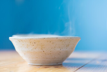 Ceramic bowl with a hot dish on a wooden table.