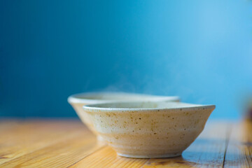 Two ceramic bowls with a hot dish on a wooden table on a blurred background.