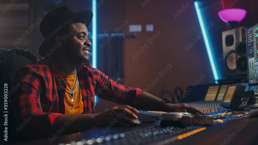 Fototapete stylish audio engineer / producer working in music recording studio, uses mixing board and software 