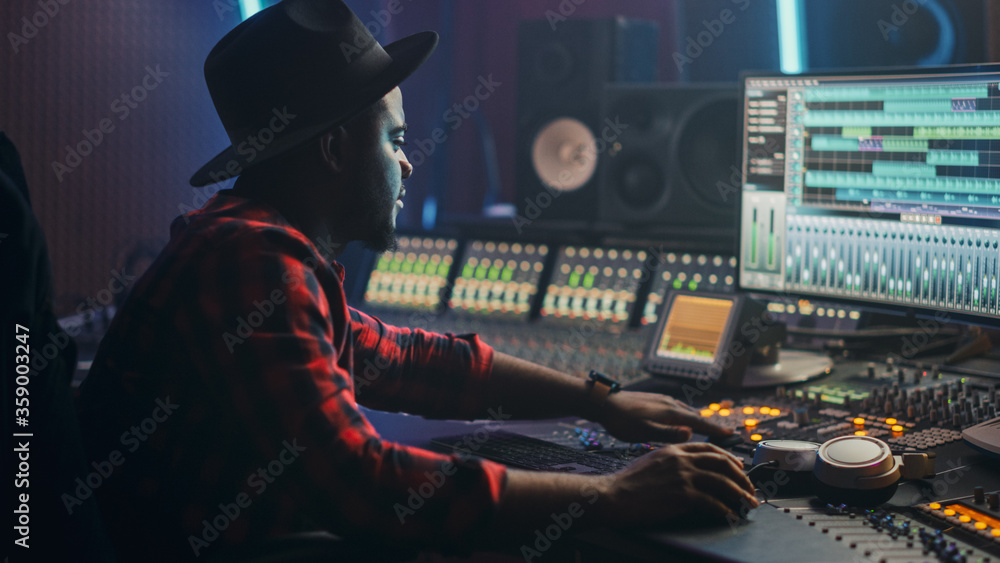 Poster Energetic Male Audio Engineer / Producer Working in Music Recording Studio, Mixing Tracks on Control Desk and Software to Create Hit Song Track. Artist Musician Enter His Studio at Sits at Workdesk